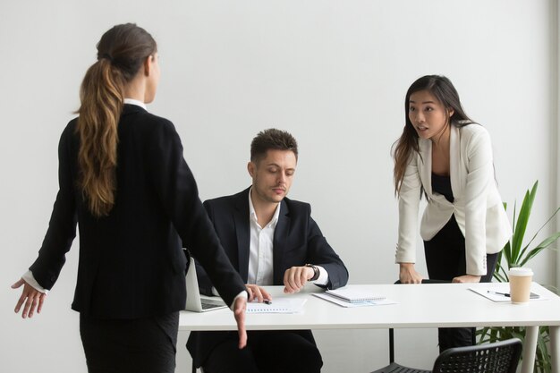 Diverse colleagues arguing about unpunctuality or missed deadline in office