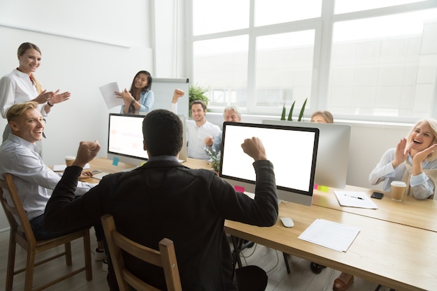 Diverse colleagues congratulating black coworker with good result or win