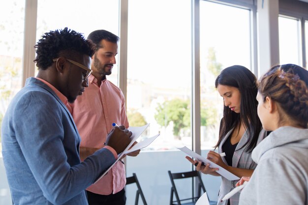 Diverse colleagues taking notes while sharing ideas