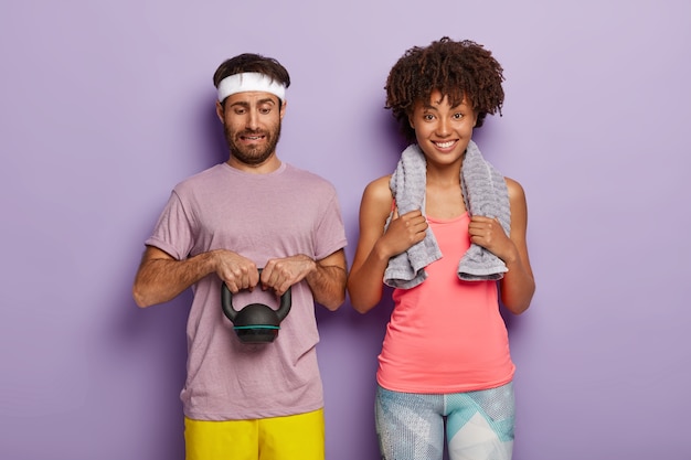 Diverse couple have cardio training. Handsome man lifts heavy weight