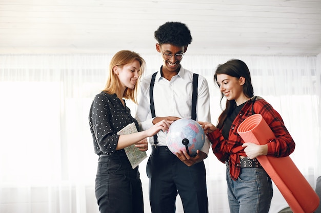 Free photo diverse friends are going for a journey. they are planning using the globe. bright living room.