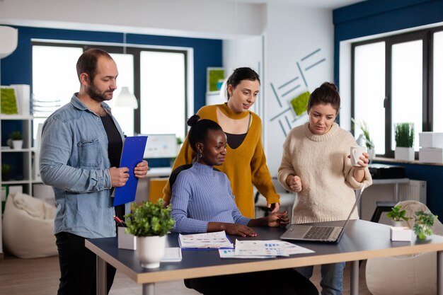 Diverse group of colleagues looking at laptop webcam during video conference meeting in start up company office