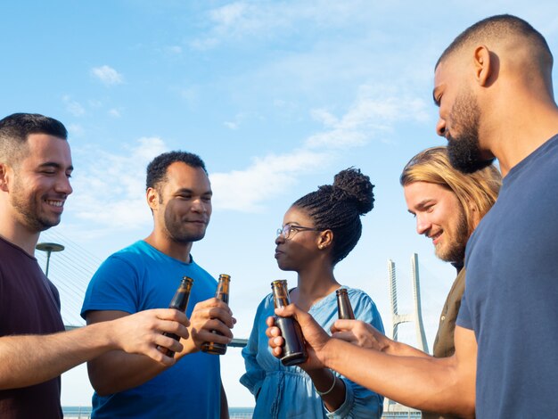 Разнообразная группа друзей, пьющих пиво на улице
