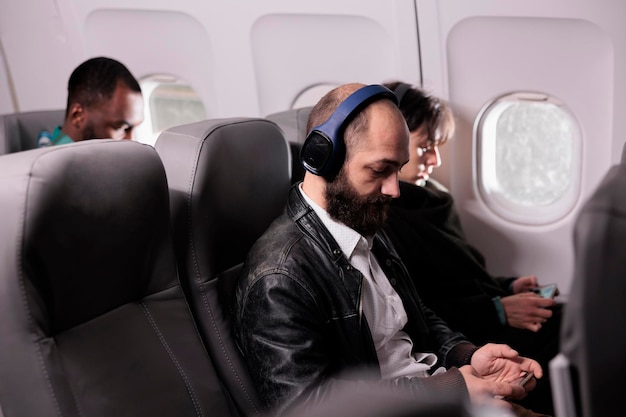 Diverse group of passengers travelling by airplane on commercial flight, flying with international airline to go on holiday trip. Travellers sitting in plane seats during aerial transportation.