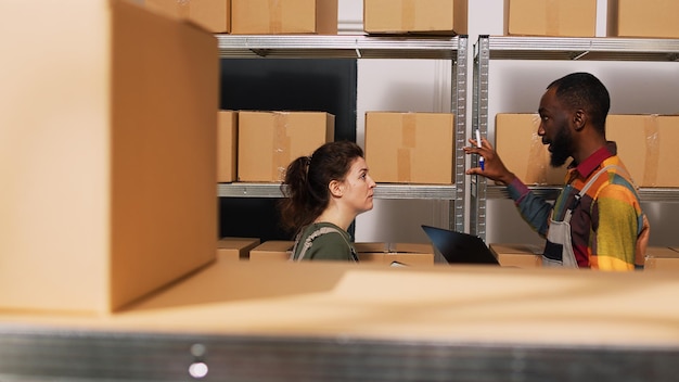 Free photo diverse people reviewing supply chain in storage room, looking at products logistics on tablet. team of employees working in manufacturing small business, quality control verification.