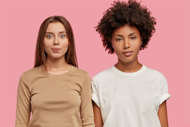 Free photo diverse serious two women stand closely to each other