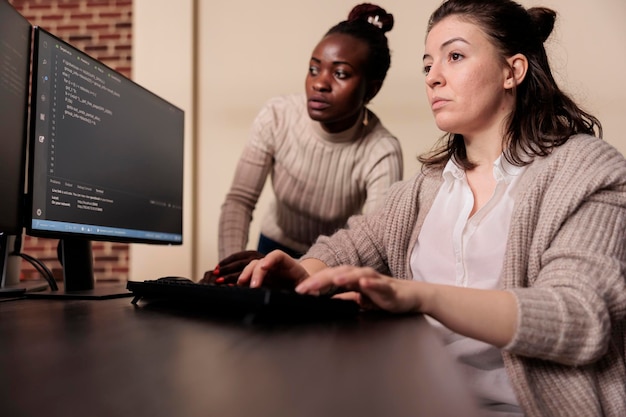 Diverse team of tech enginners talking about programming in it development agency. African american programmer compiling app language with software developer, innovating online server algorithms.