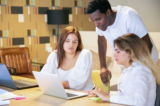 Разнообразная команда вместе смотрит презентацию на компьютере