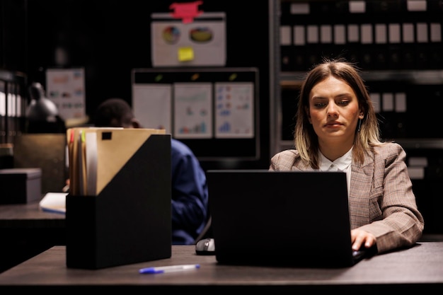 Free photo diverse team working overtime at criminal investigation, searching for evidence in arhive room. private detectives working through every clue at the crime scene, analyzing criminology report