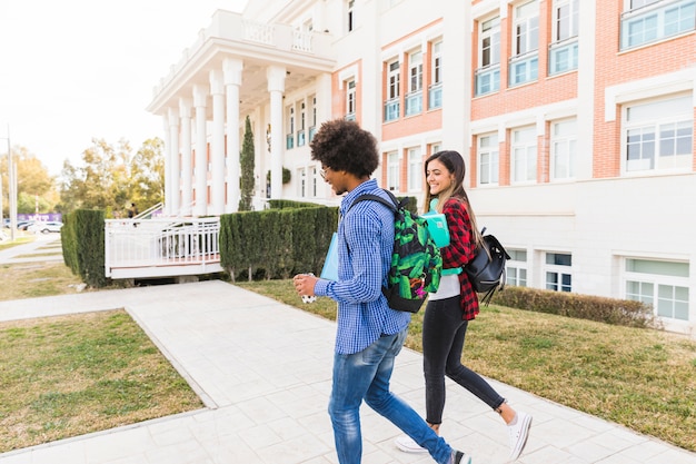 Diverse teenage couple student walking together outside the university building