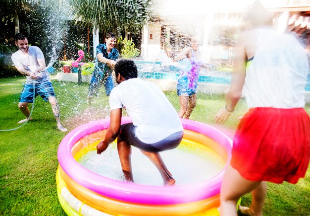 Diverse young adult splashing water in backyard