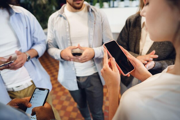 Diverse young people colleagues working on mobile phones together in office