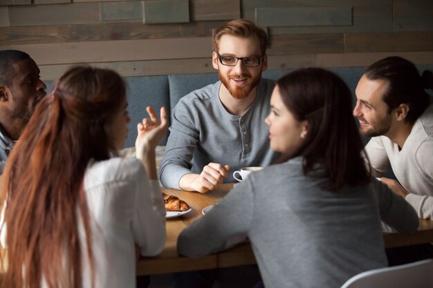 Разнообразные молодые люди разговаривают и веселятся вместе в кафе