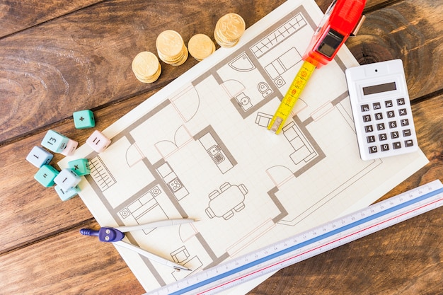 Free photo divider, ruler, math blocks, calculator, stacked coins and blueprint on wooden desk