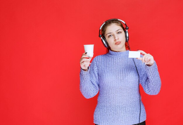 Dj girl with a coffee cup in the hand showing her business card. 