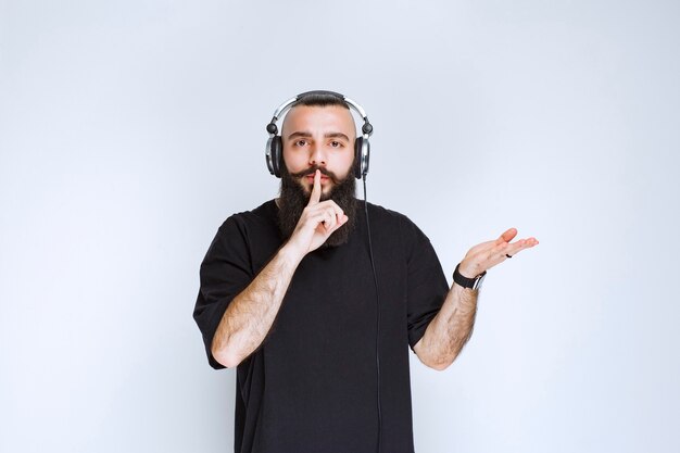 DJ with beard wearing headphones and asking for silence.