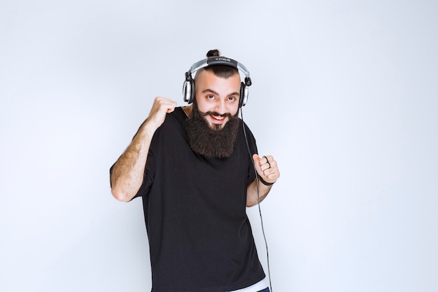 Dj with beard wearing headphones dancing and feeling active.