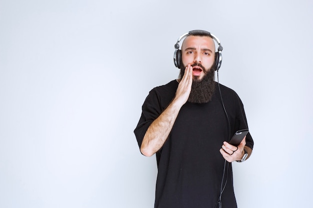 Dj with beard wearing headphones and gets surprized by the playlist.