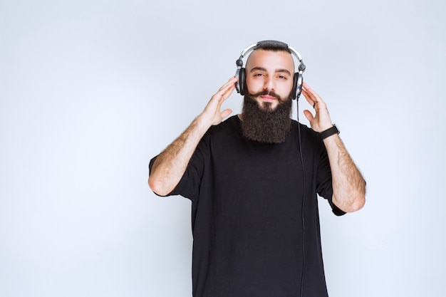 Dj with beard wearing headphones and listening to the music.