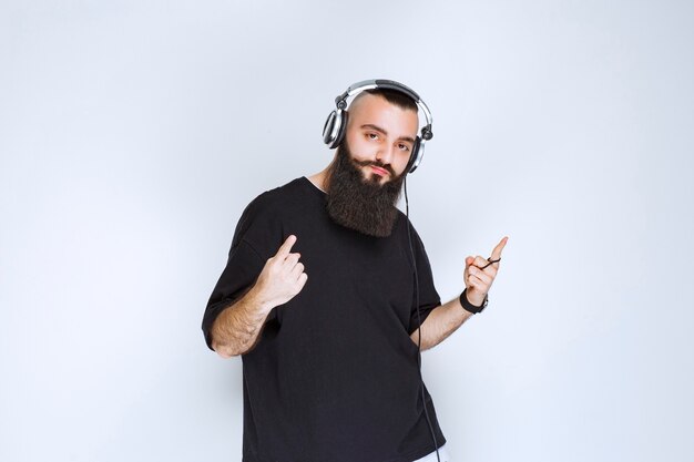 Dj with beard wearing headphones and pointing up.