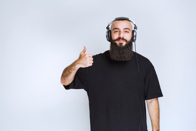 DJ with beard wearing headphones and showing positive hand sign.