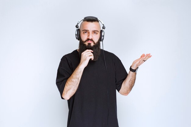 DJ with beard wearing headphones, showing right side and gets surprized.