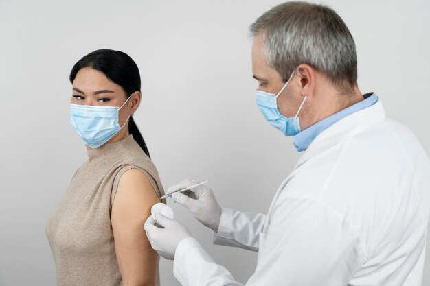 Doctor administering vaccine shot to female patient