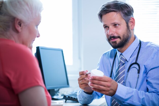 Doctor assisting a bottle of drug to patient in medical office