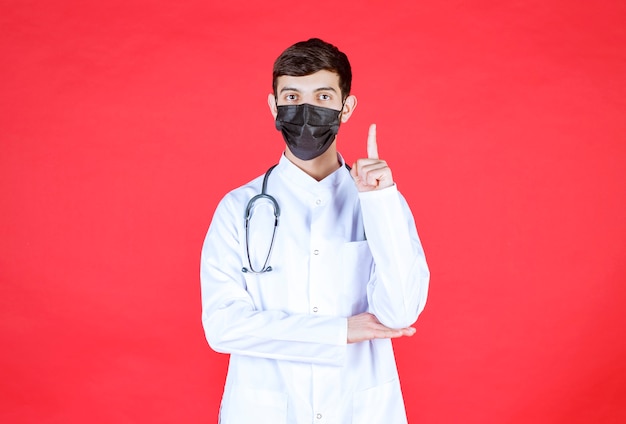 Doctor in black mask with stethoscope on the neck.