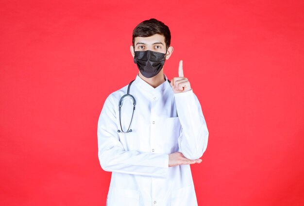 Doctor in black mask with stethoscope on the neck. 