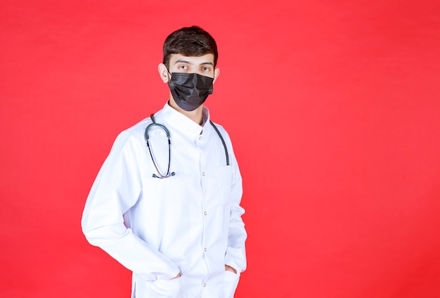 Doctor in black mask with stethoscope on the neck. 