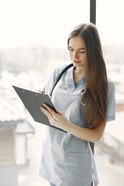 Doctor in blue uniform. Girl with a stethoscope around her neck. Woman with long hair.