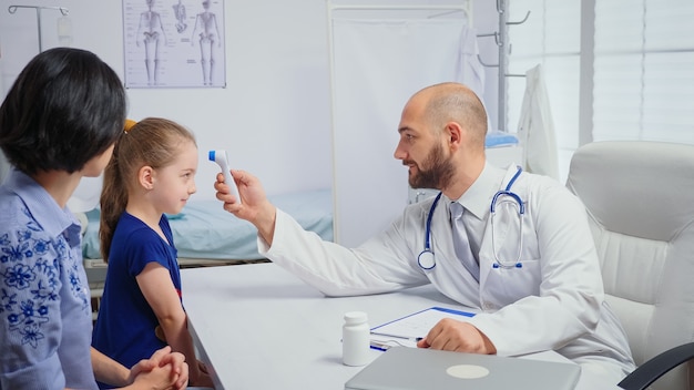 Doctor checking evolution of the fever while nurse taking notes. Healthcare physician specialist in medicine providing health care services radiographic treatment examination in hospital cabinet