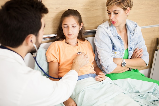 Free photo doctor checking her patient heart  in hospital