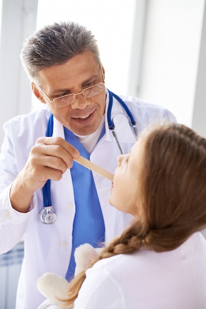 Doctor checking his patient's throat