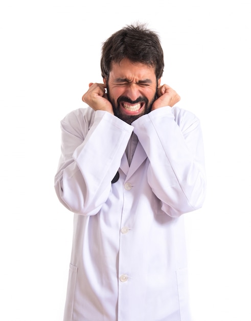 Doctor covering his ears over white background