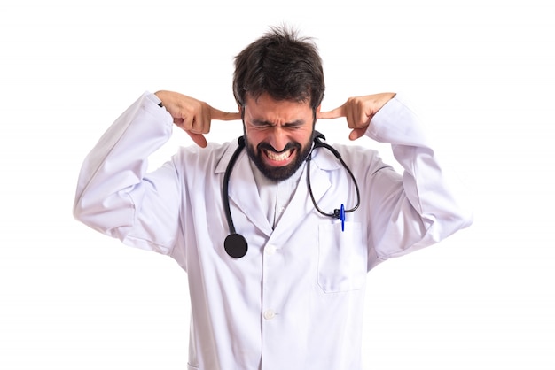 Doctor covering his ears over white background