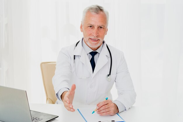 Doctor at desk holding out his hand
