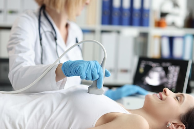 병원에서 환자의 유방에 대한 초음파 검사를 하는 의사