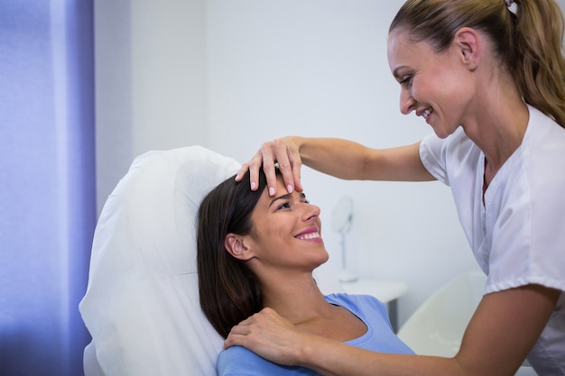 Doctor examining female patients face at clinic