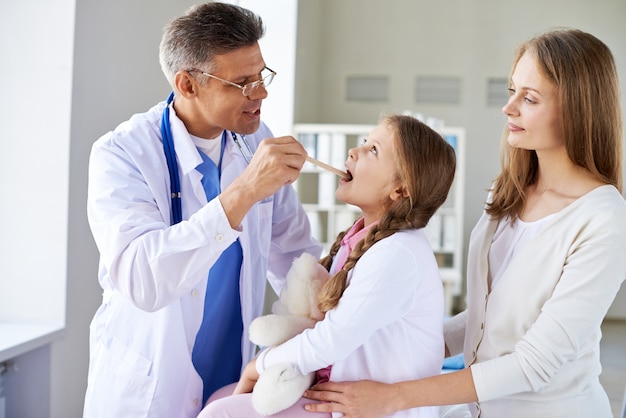 Medico che esamina bambina con la madre in ufficio medico