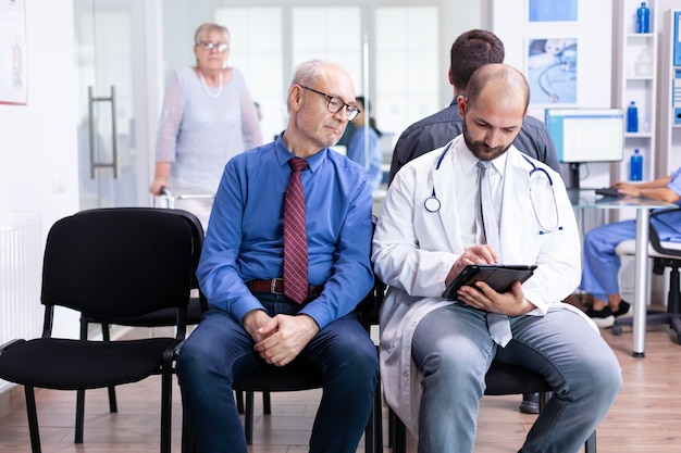 Doctor explaining test results to senior man in hospital waiting area