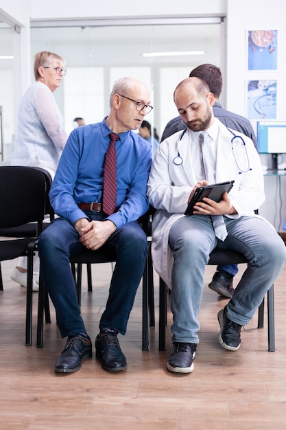 Doctor explaining test results to senior man in hospital waiting area