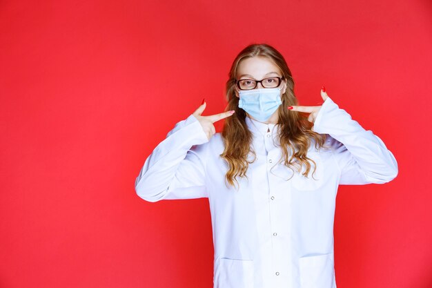 Doctor in face mask pointing to herself .