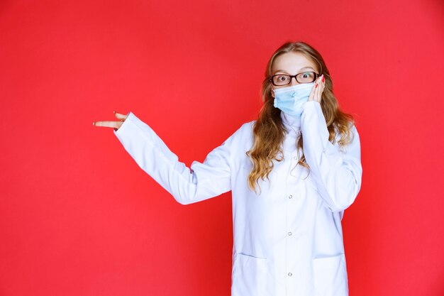 Doctor in face mask pointing to the left .