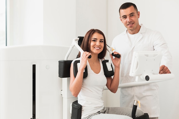 Doctor and female patient posing near medical machine