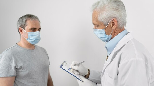 Doctor filling information on notepad before vaccination of male patient