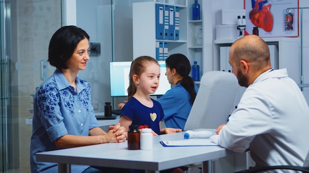 Doctor giving high five with little patient in medical office. Healthcare practitioner, physician, specialist in medicine providing health care services consultation diagnostic treatment in hospital.