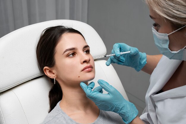 Doctor giving young woman lip fillers high angle