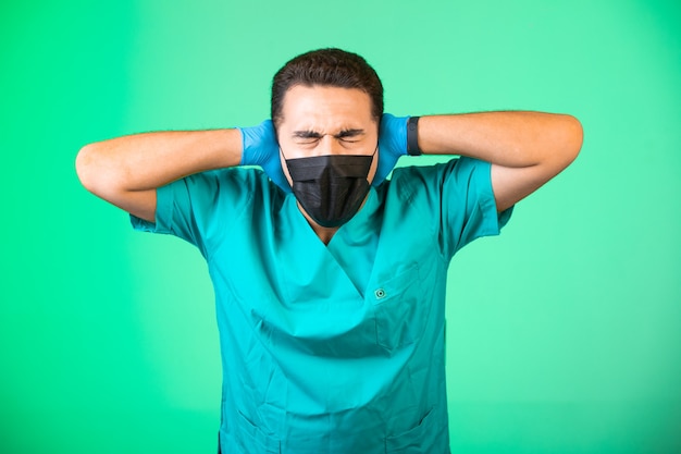 Dottore in uniforme verde e maschera per il viso che copre le orecchie.